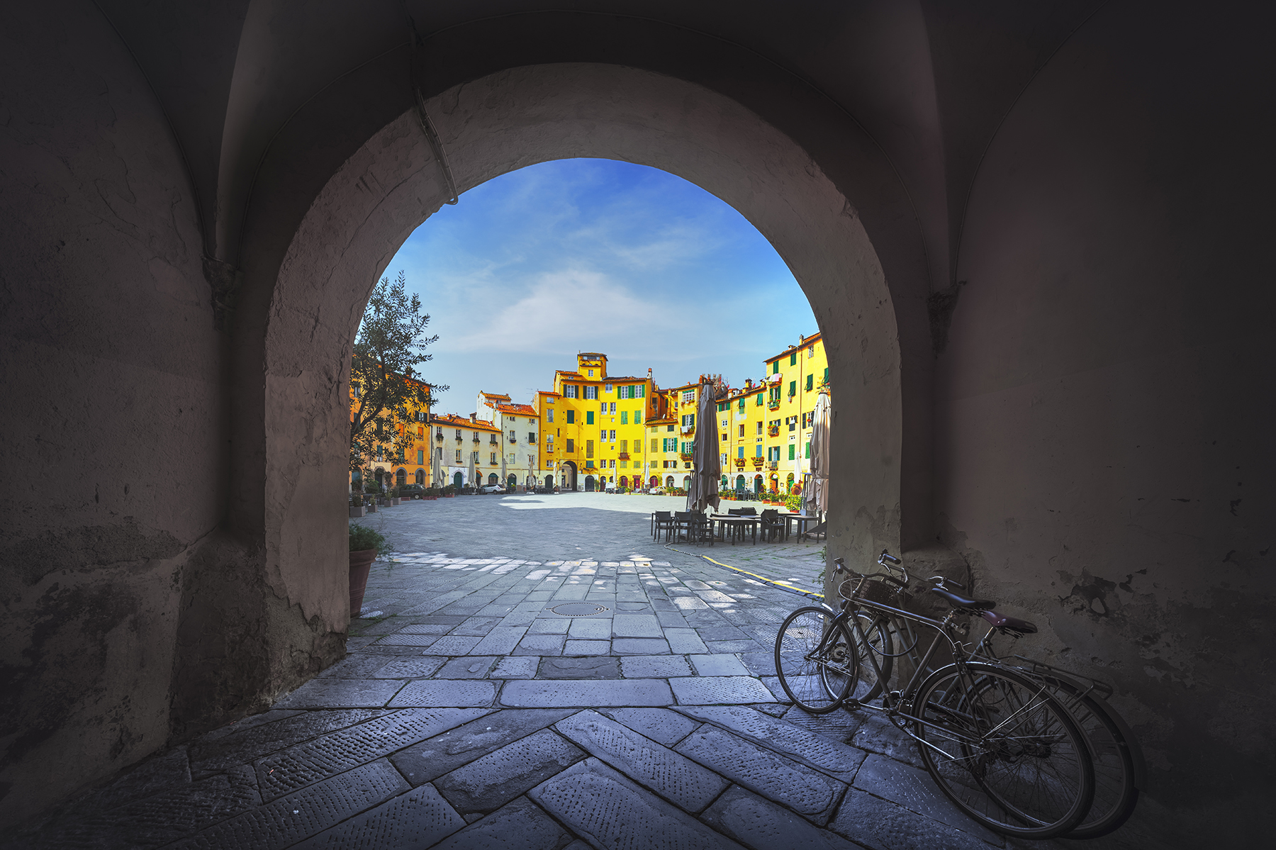 Lucca, historic Piazza dell' Anfiteatro public square from entrance arch and two old bikes. Tuscany, Italy, Europe.